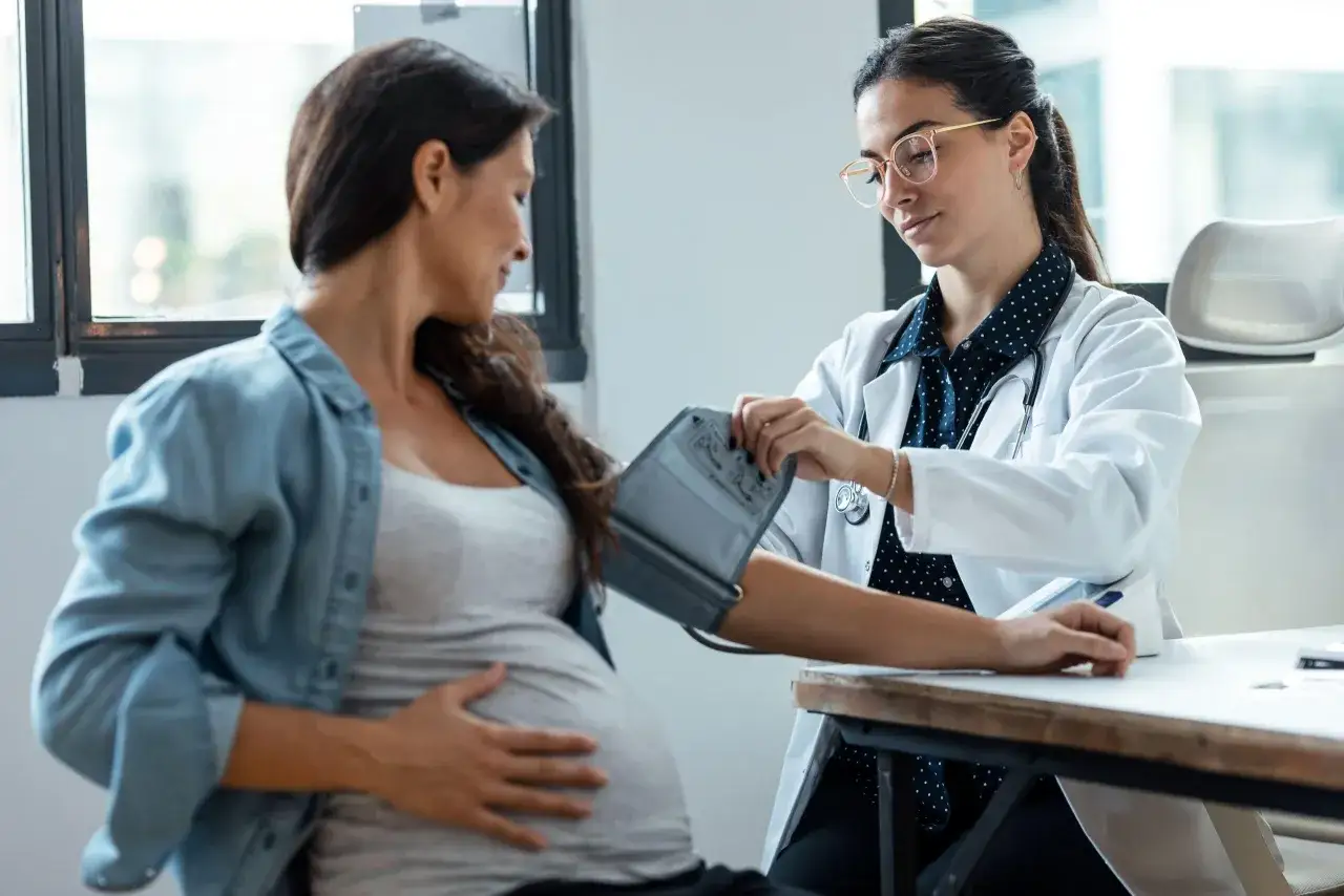 Medico controlla la pressione a una donna incinta, monitorando la salute per prevenire la pressione bassa in gravidanza.