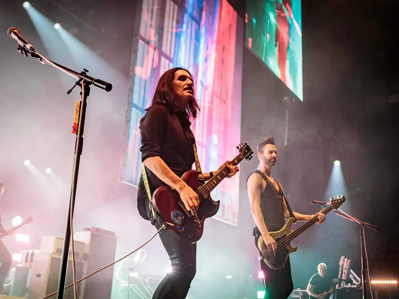 Les membres de Placebo sur sc&egrave;ne, Brian Molko &agrave; la guitare et Stefan Olsdal &agrave; la basse, sous des lumi&egrave;res vives.
