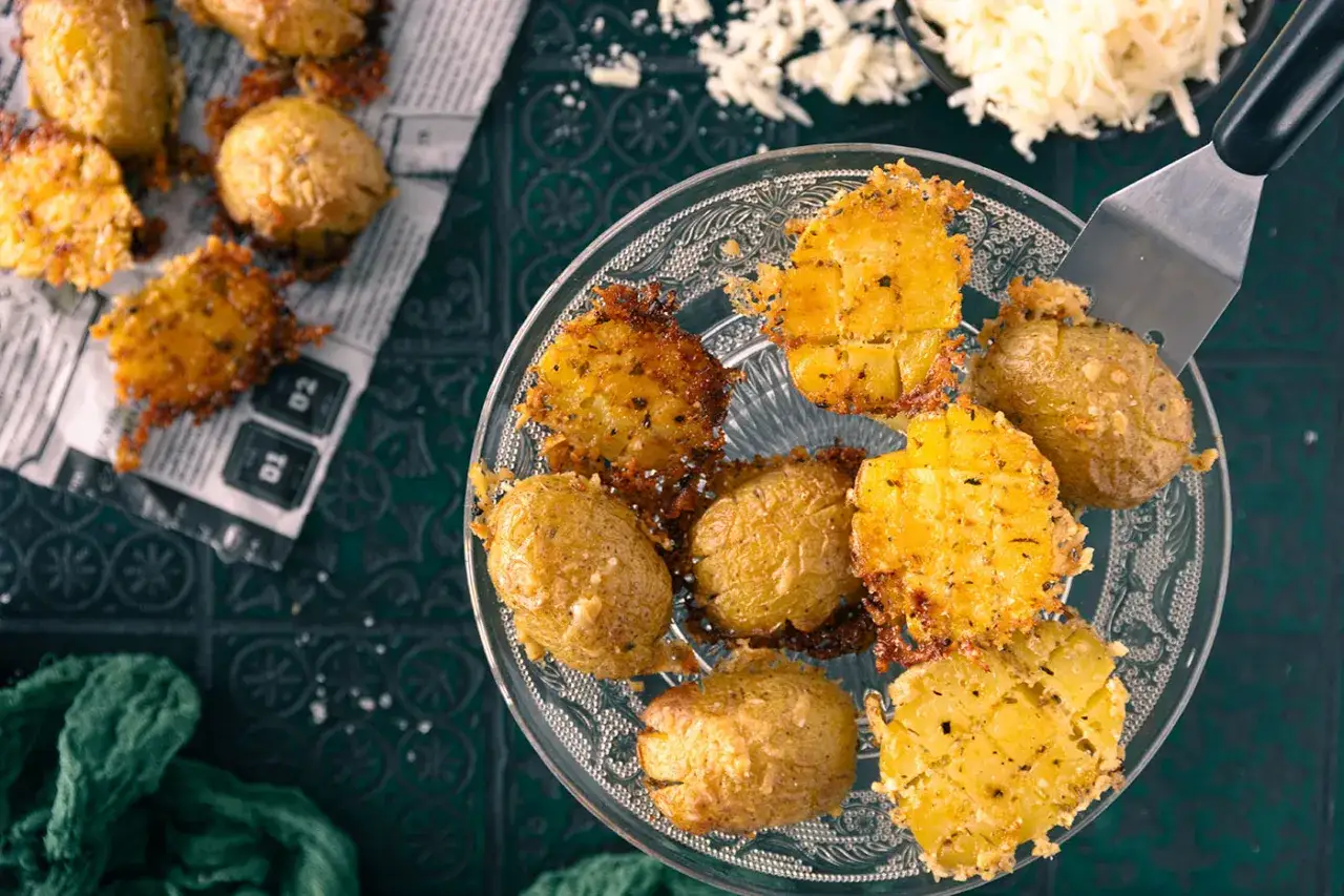 Knusprige parmesan kartoffeln, goldbraun gebacken und mit Käse überbacken, werden auf einer Servierplatte präsentiert.