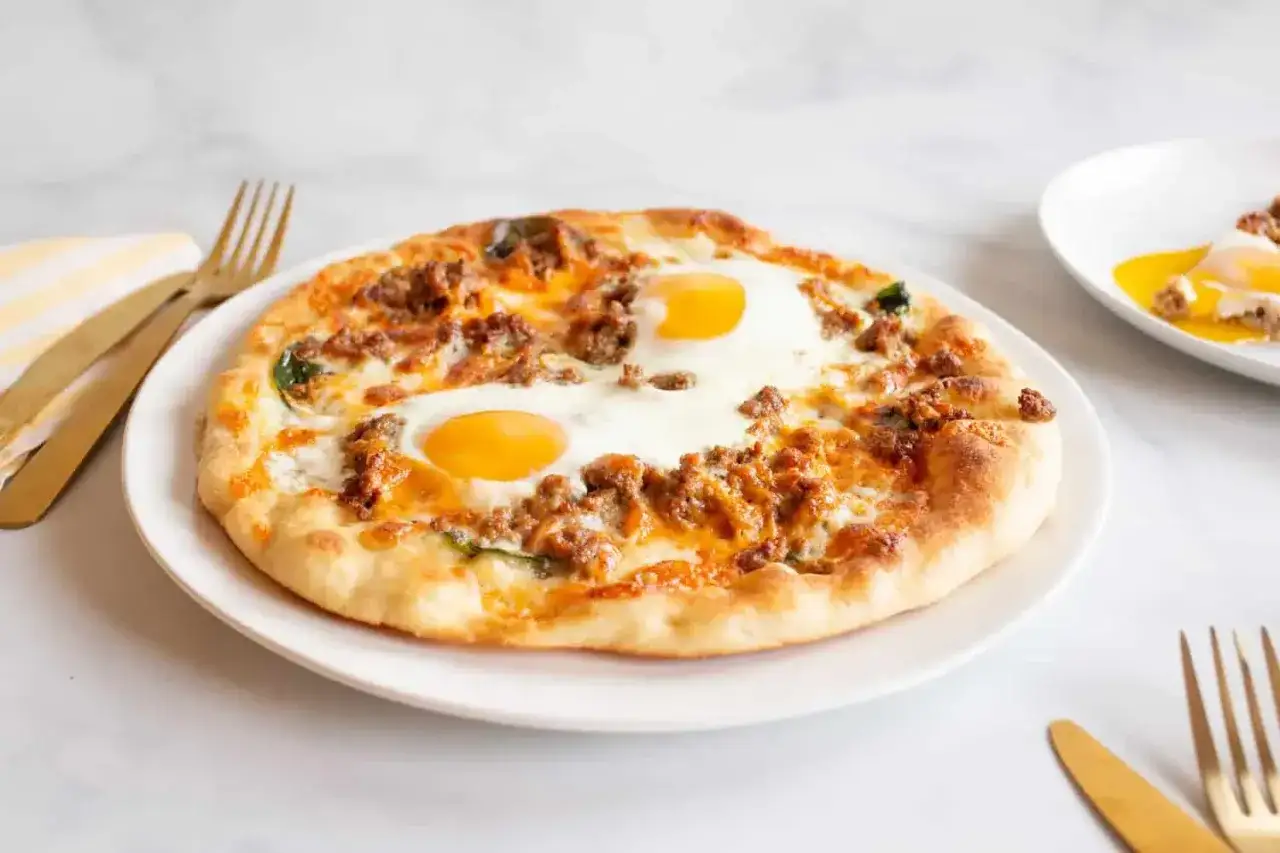 Pyszna pizza z jajkiem, mielonym mięsem i serem. Idealna na śniadanie lub brunch.