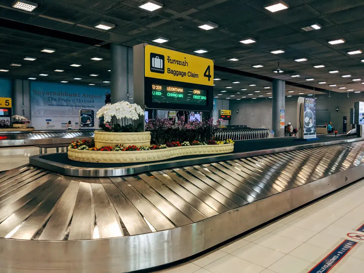 Lotnisko Suvarnabhumi, taśma do odbioru bagażu po podróży. Kwiaty zdobią taśmę.