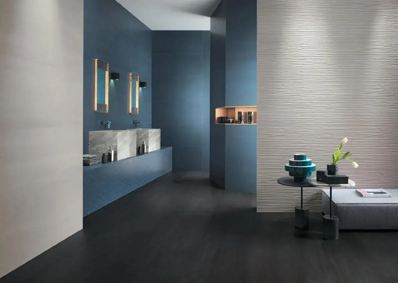 Bagno moderno con pareti blu intenso e un'elegante parete con laminato effetto metallo. Pavimento scuro e lavabi in marmo.