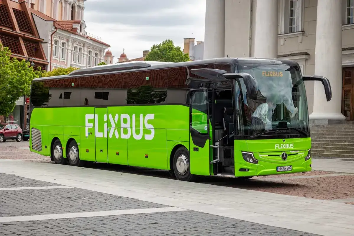 Zielony autobus FlixBus stoi na brukowanym placu. Idealny na podróż, gdy szukasz **znizki FlixBus**.