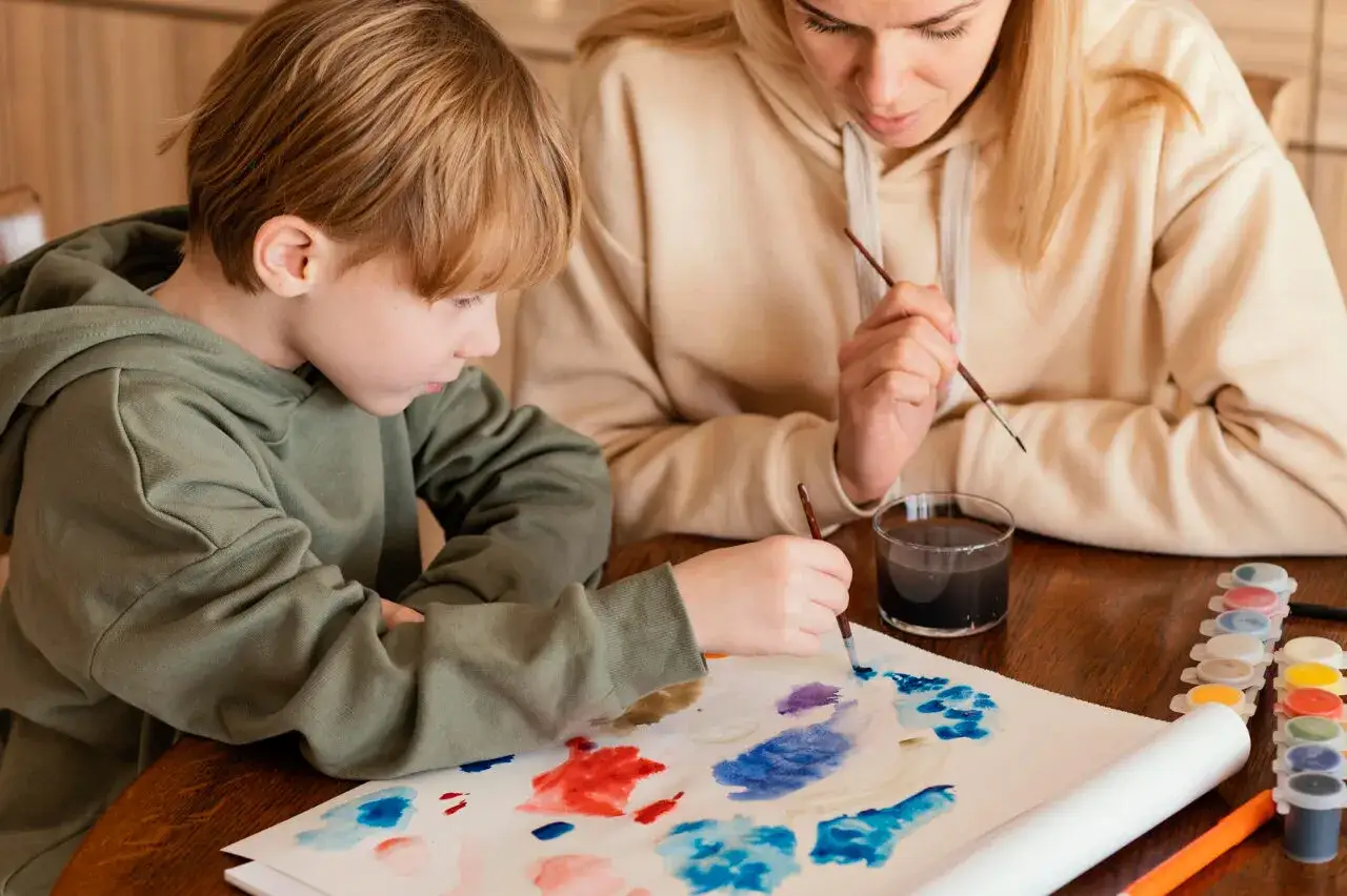 Un bambino e una terapista ABA dipingono insieme, un esempio di come un terapista ABA cosa fa per stimolare la creativit&agrave; e le abilit&agrave;.