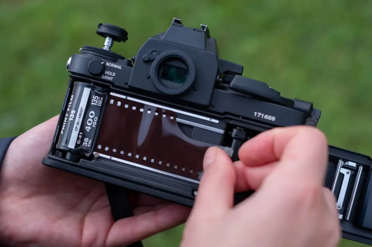 Loading 135 film into a camera. The roll of film is visible, ready to capture memories.