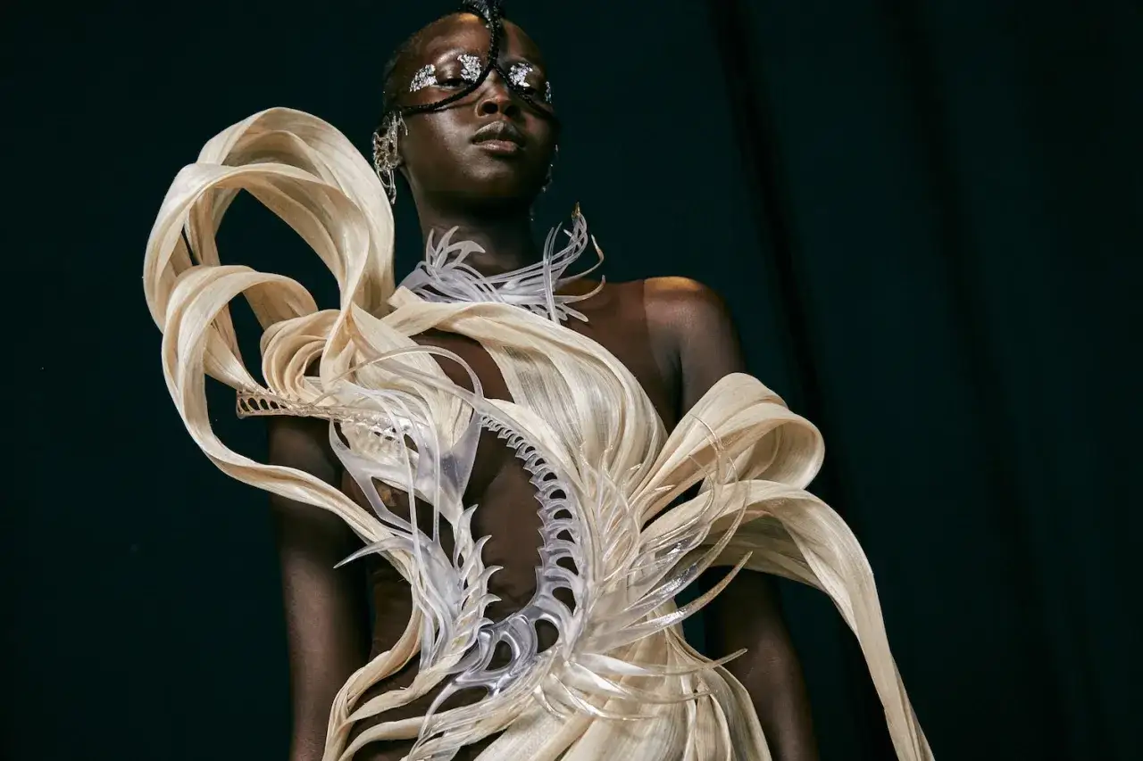 Mannequin portant une robe spectaculaire, œuvre d'impression 3D textile, aux formes organiques et futuristes.