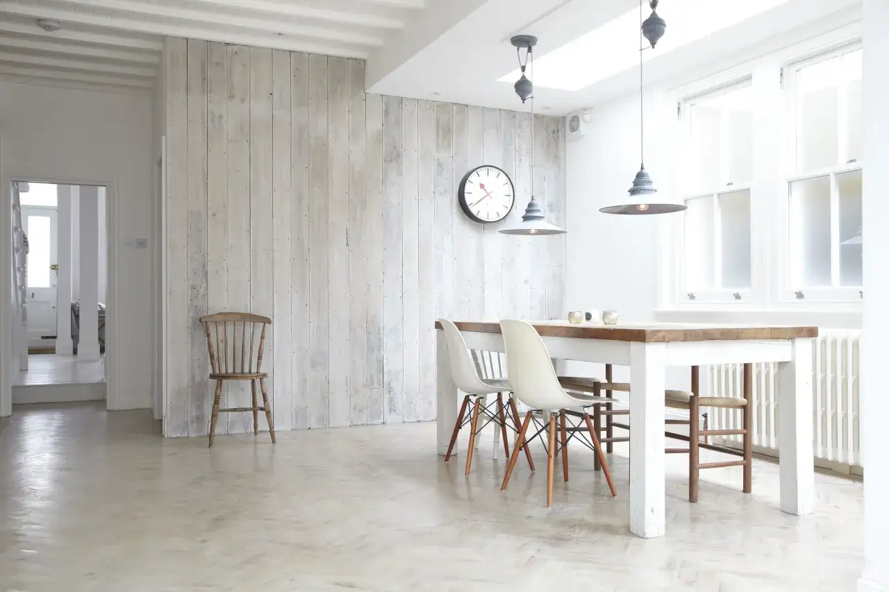 Una parete in legno fai da te dona un tocco rustico a questa sala da pranzo luminosa, con tavolo, sedie moderne e un vecchio sedia di legno.