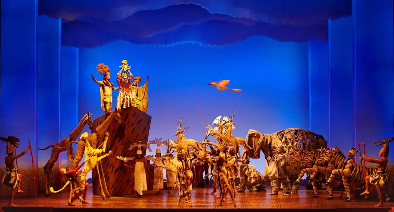 La sc&egrave;ne du Roi Lion Mogador s'anime : Rafiki pr&eacute;sente Simba, entour&eacute; d'animaux magnifiques et de danseurs.