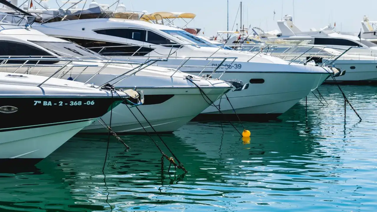 Yacht ormeggiare significato: barche bianche ormeggiate in un porto, con riflessi sull'acqua turchese.