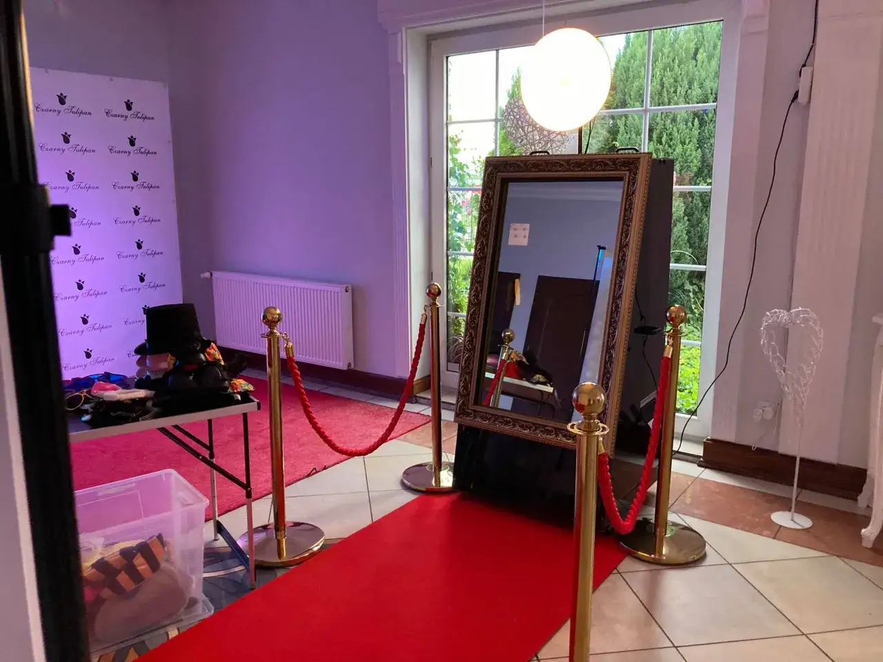 Elegancki fotolustro na wesele z czerwonym dywanem i akcesoriami do zdjęć. Idealne miejsce na niezapomniane pamiątki z przyjęcia.