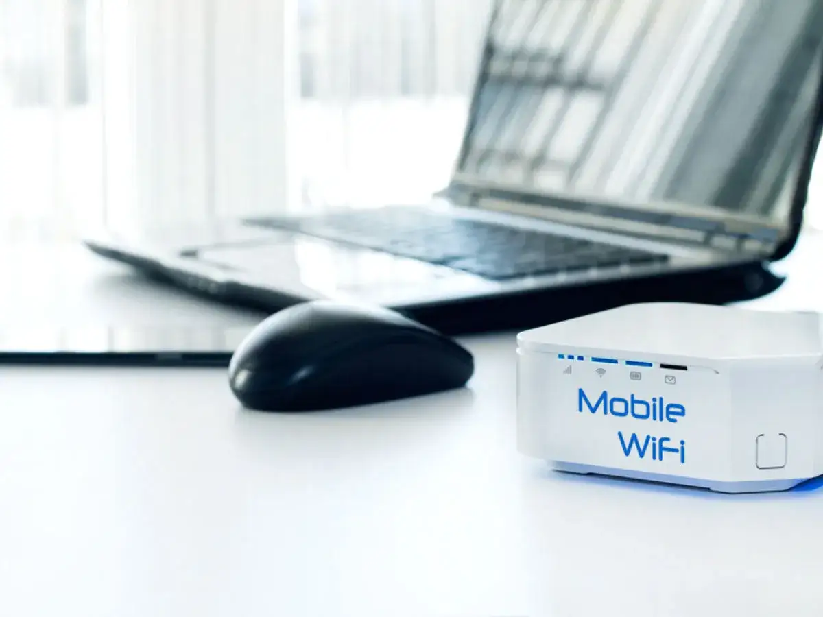 Mobilny router Wi-Fi, idealny do internetu na kartę bez umowy. Obok laptop, myszka i tablet.
