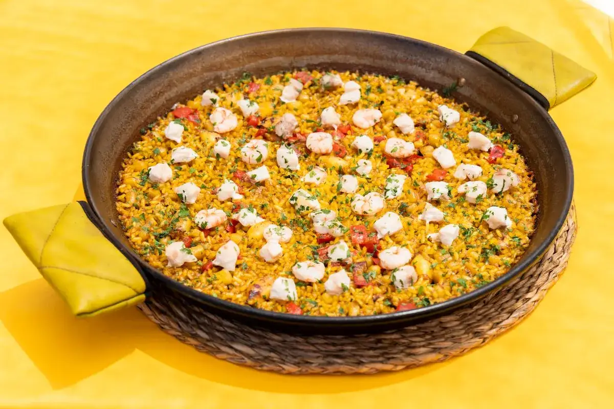 Paella de marisco y pescado, perfecta para saber donde comer en Almería. Arroz amarillo con gambas, trozos de pescado blanco y pimientos rojos.