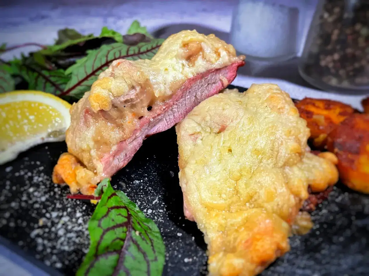Zarte Scheiben eines **Steak au Four** mit knuspriger Kruste, serviert mit Salat und Zitronenspalte.