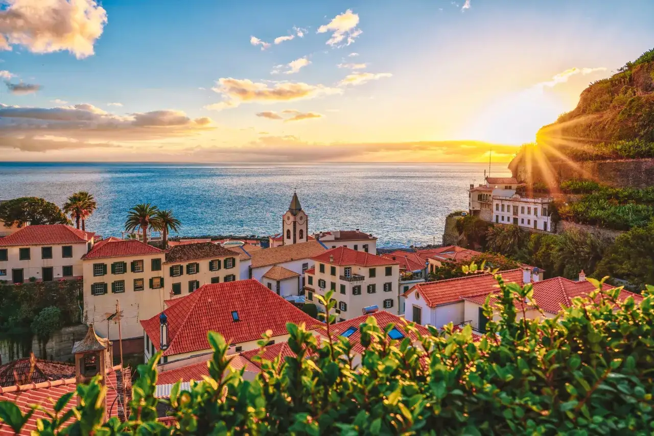 Sonnenuntergang über Ponta do Sol, Madeira. Rote Dächer und das Meer im goldenen Licht.