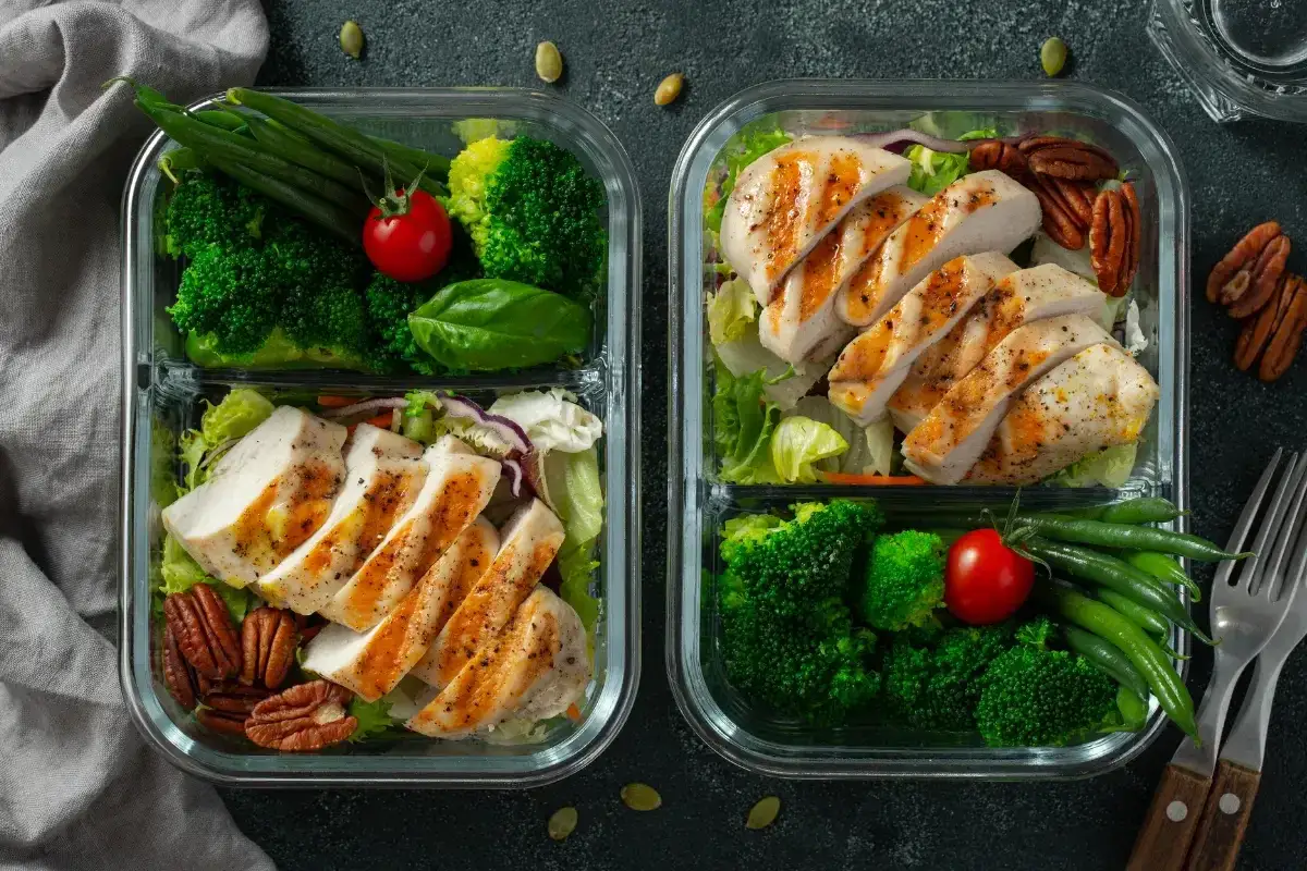 Deux boîtes repas avec poulet grillé, brocolis, haricots verts et noix. Parfait pour un encas sportif sain et équilibré.