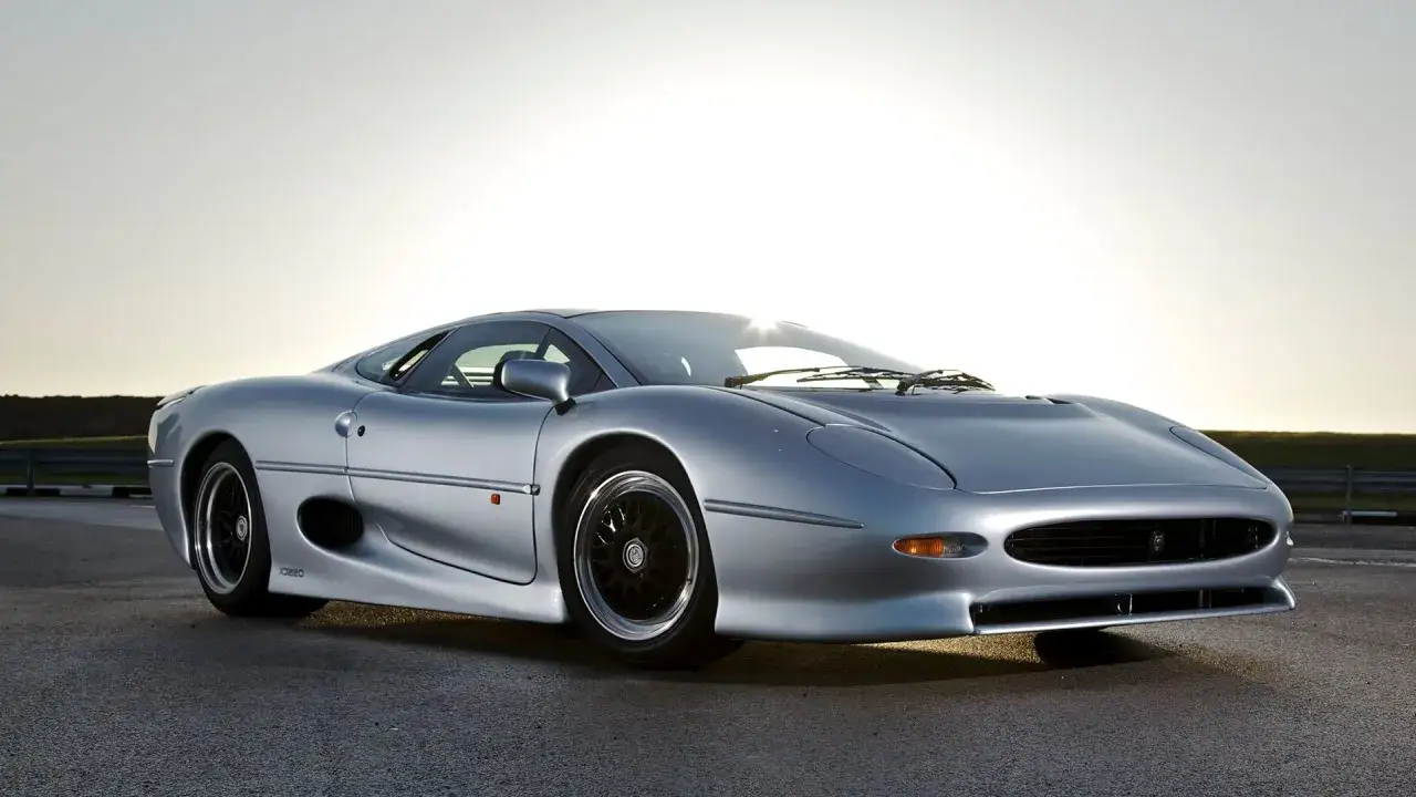Srebrny Jaguar XJ220 na tle zachodzącego słońca. Ikona motoryzacji z lat 90.