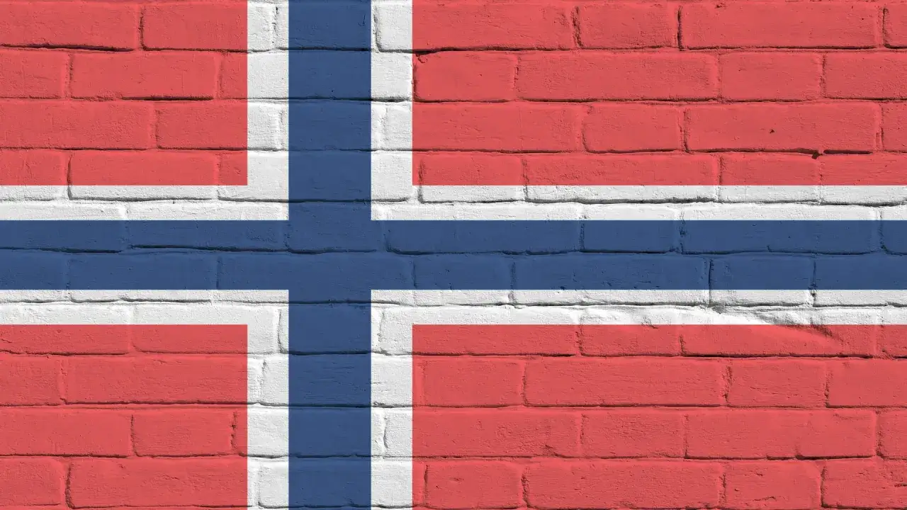 Flaga Norwegii na ceglanej ścianie. Planujesz podróż i zastanawiasz się, czy w Norwegii jest roaming?