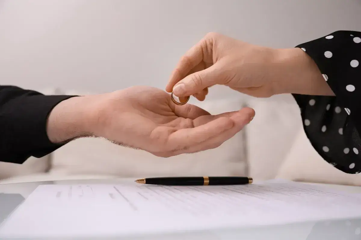 Dłoń oddaje obrączkę, symbol końca małżeństwa. Zastanawiasz się, jak długo czeka się na rozwód od złożenia wniosku?