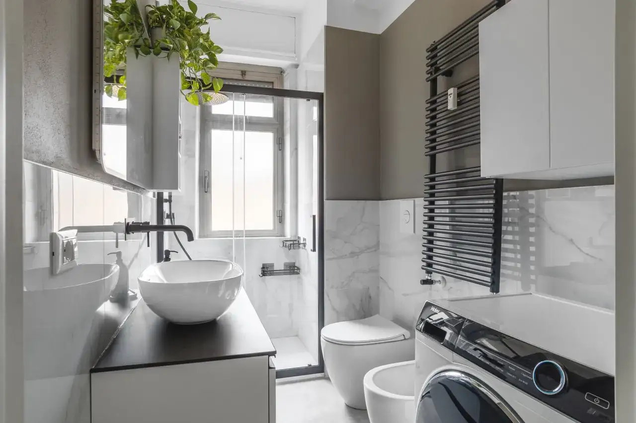 Bagno 4 mq pianta: lavabo, doccia, WC, bidet e lavatrice in uno spazio compatto ma funzionale, con un tocco verde da una pianta pensile.