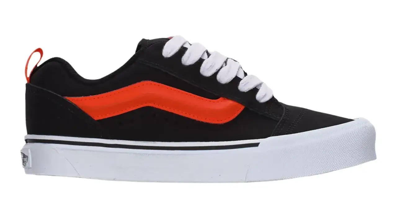 Czarny Vans z pomarańczowym paskiem i białą podeszwą. Czy vansy są wygodne? Ten model wygląda na bardzo komfortowy.