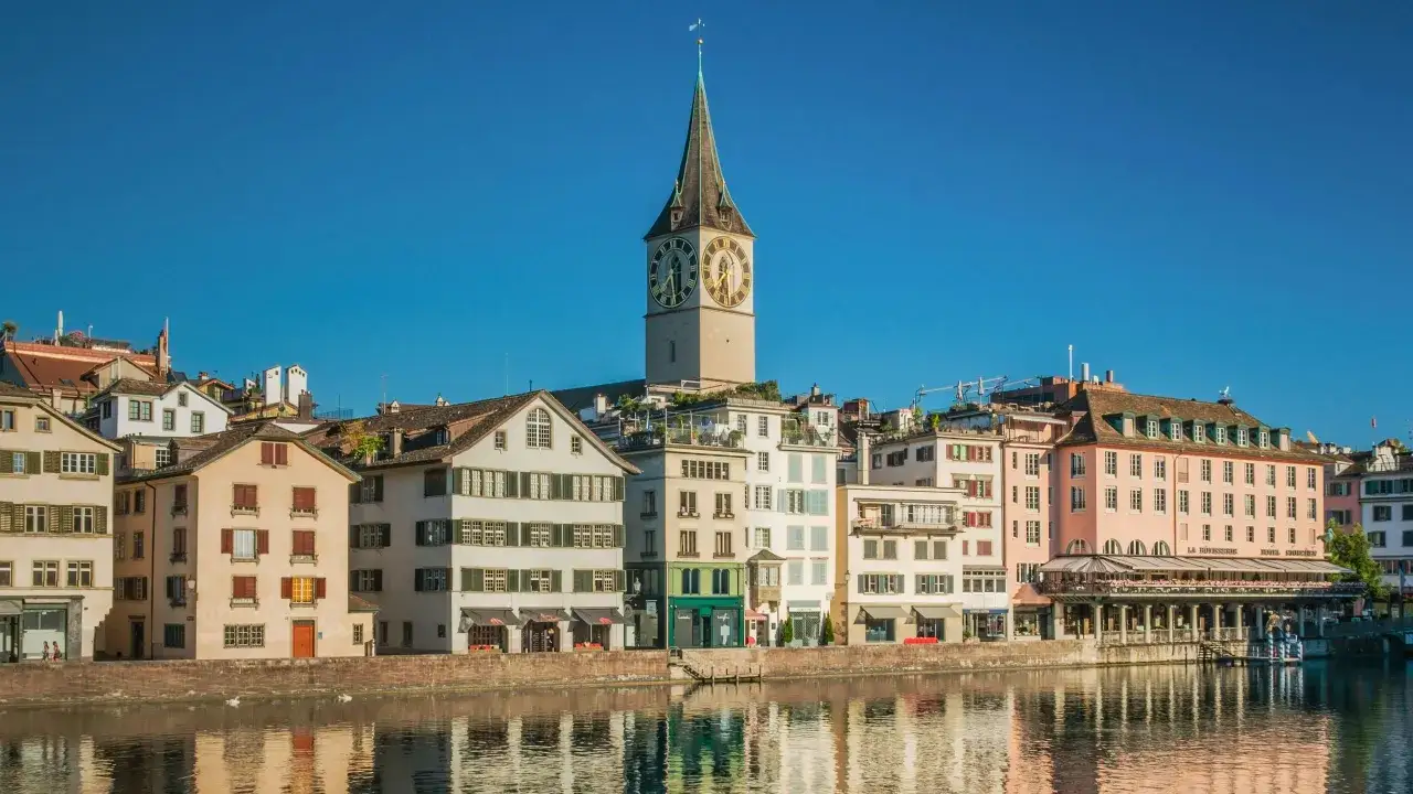 Z&uuml;rich, die teuerste Stadt Europas, mit dem Kirchturm und bunten H&auml;usern am Wasser.