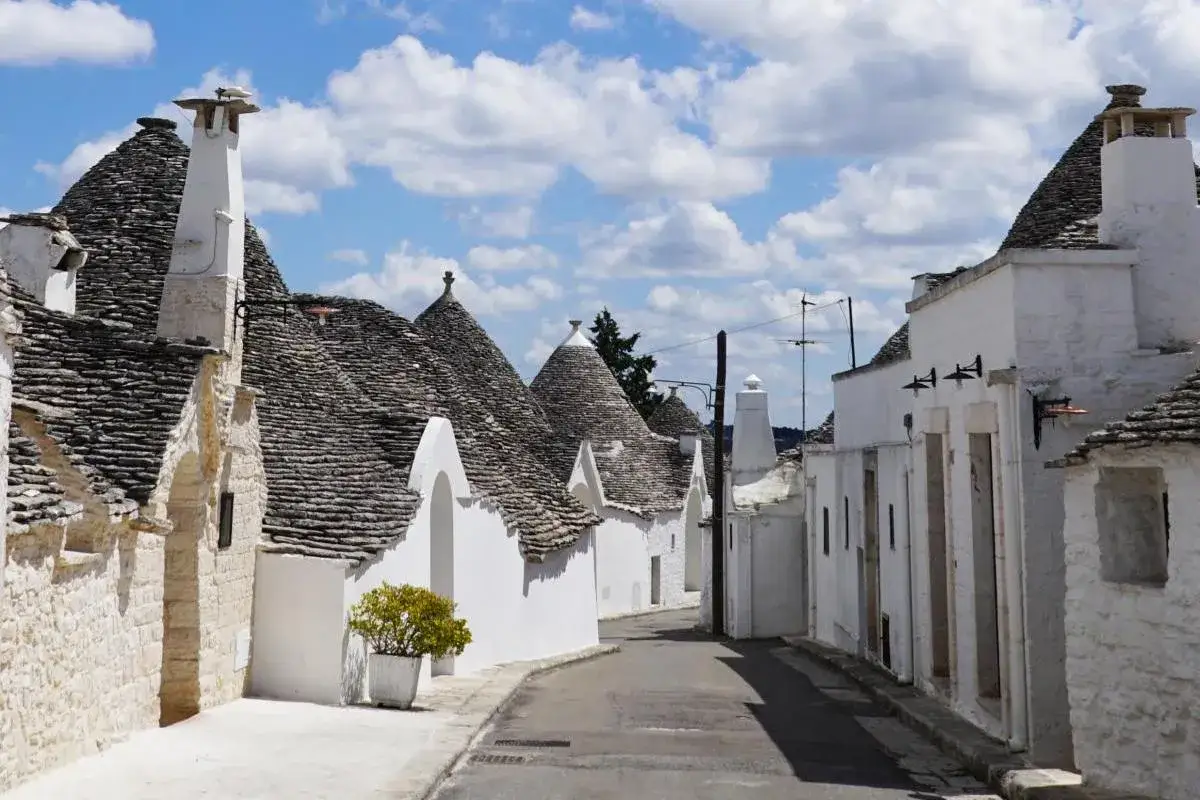 Un vicolo tra i caratteristici trulli di Alberobello, patrimonio UNESCO, con i loro tetti conici in pietra.