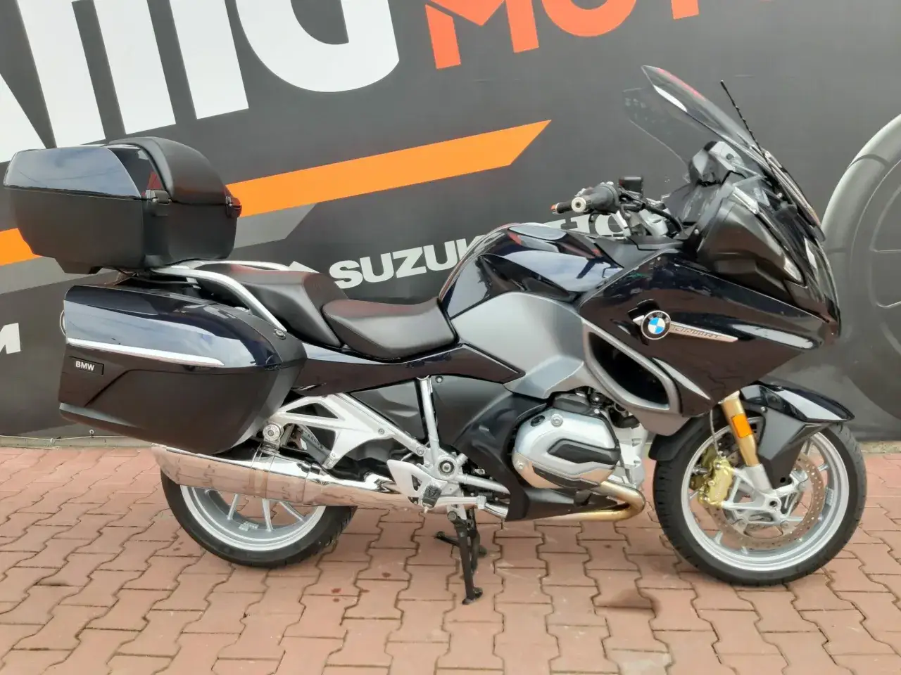Ciemnoniebieski motocykl turystyczny BMW R 1200 RT z kuframi, gotowy na długie podróże.