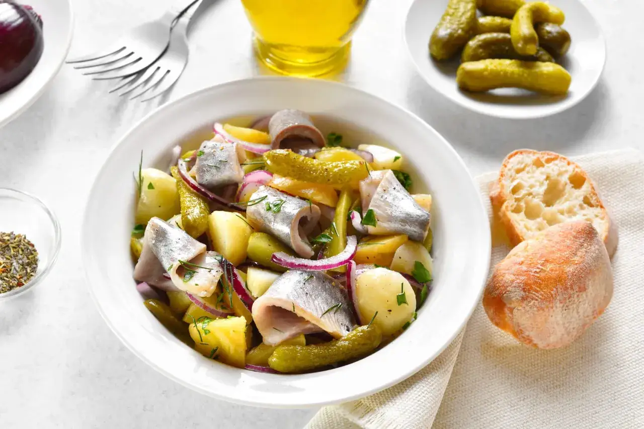Salade de harengs à l'huile avec pommes de terre, oignons rouges et cornichons. Une recette simple et savoureuse.