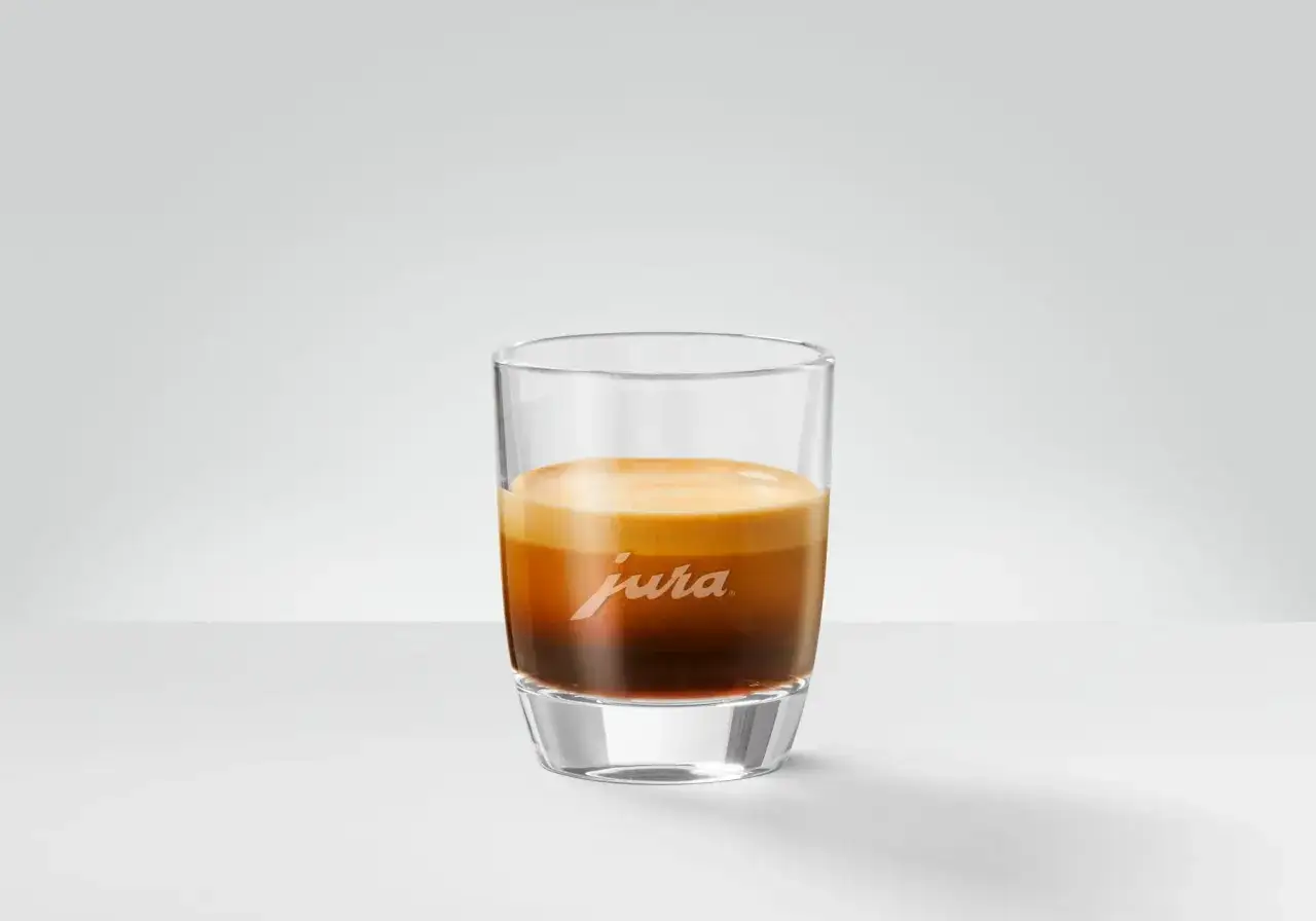 En perfekt ristretto kaffe med gyllene crema i ett stilrent glas med Jura-logotypen.