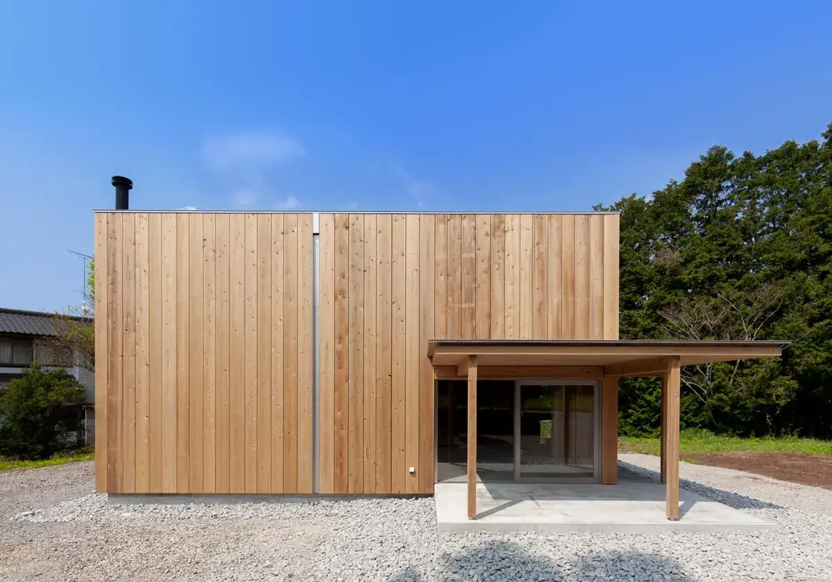 Moderna casa con una **estructura de madera para casa** revestida de tablones verticales. Un porche de madera protege la entrada acristalada.