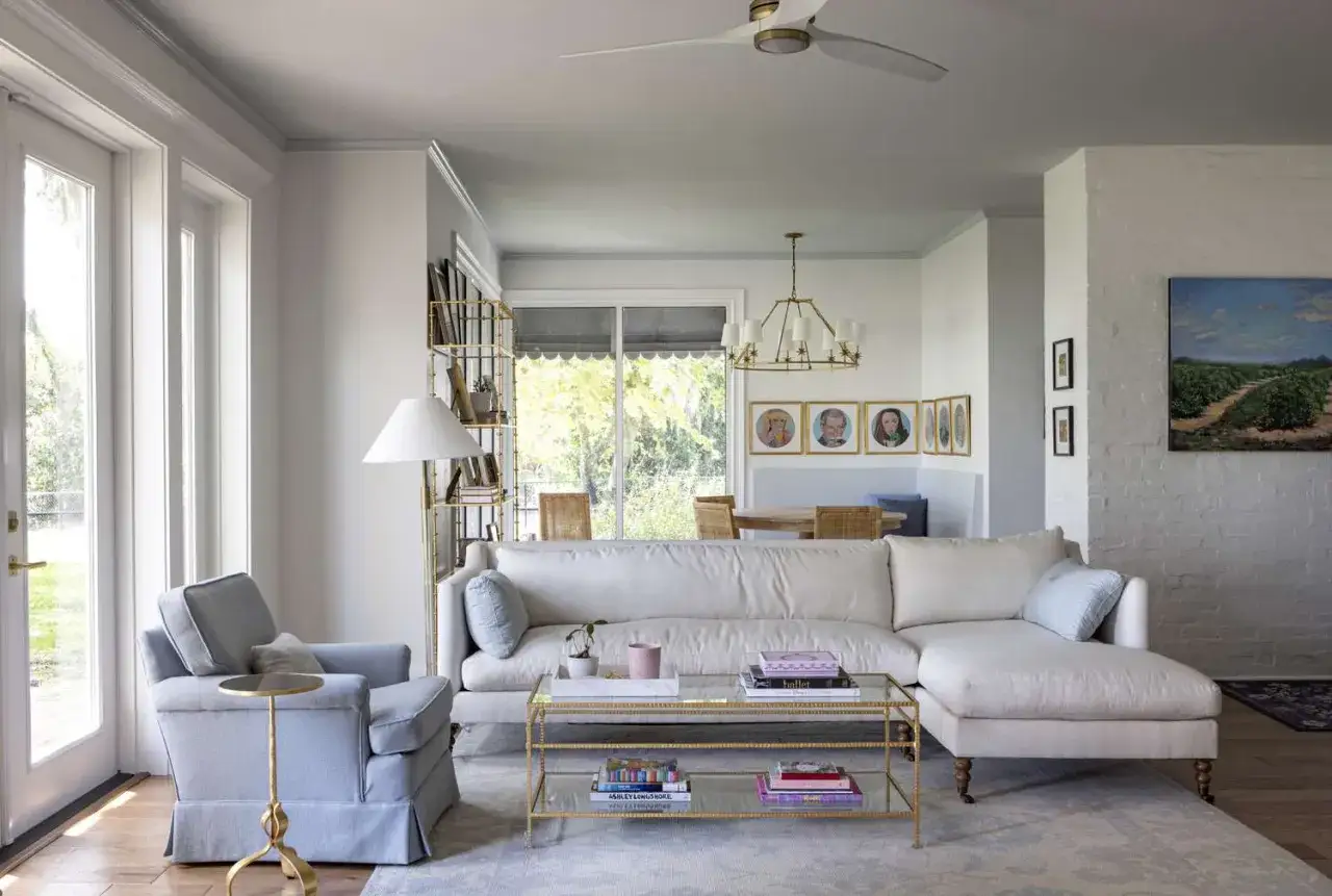 Ein helles Wohnzimmer mit einem beigen Sofa und einem blauen Sessel. Die W&auml;nde sind in einem sanften Grau gestrichen, welche farbe wirkt beruhigend.