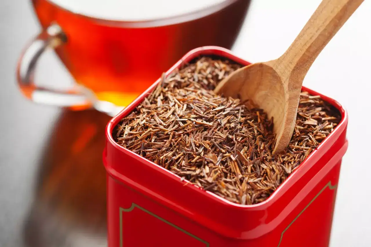 Czerwona herbata rooibos w metalowym pudełku, gotowa do zaparzenia. Bez kofeiny, idealna na relaks.