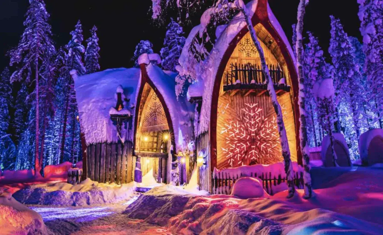 Noche mágica en Finlandia con niños. Casas nevadas iluminadas con luces de colores y copos de nieve gigantes.