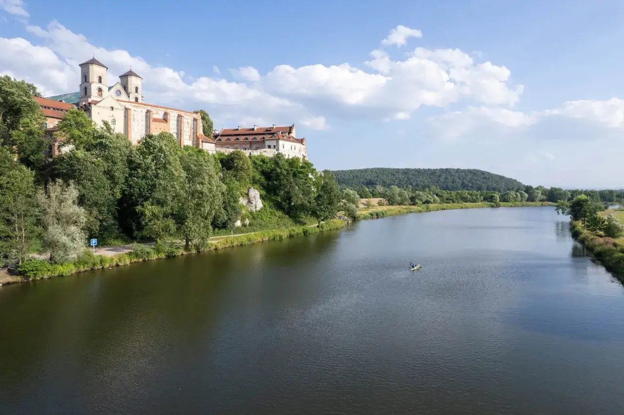 Opactwo Benedyktynów w **Tieńcu** na wzgórzu nad Wisłą. W oddali widać kajakarzy.