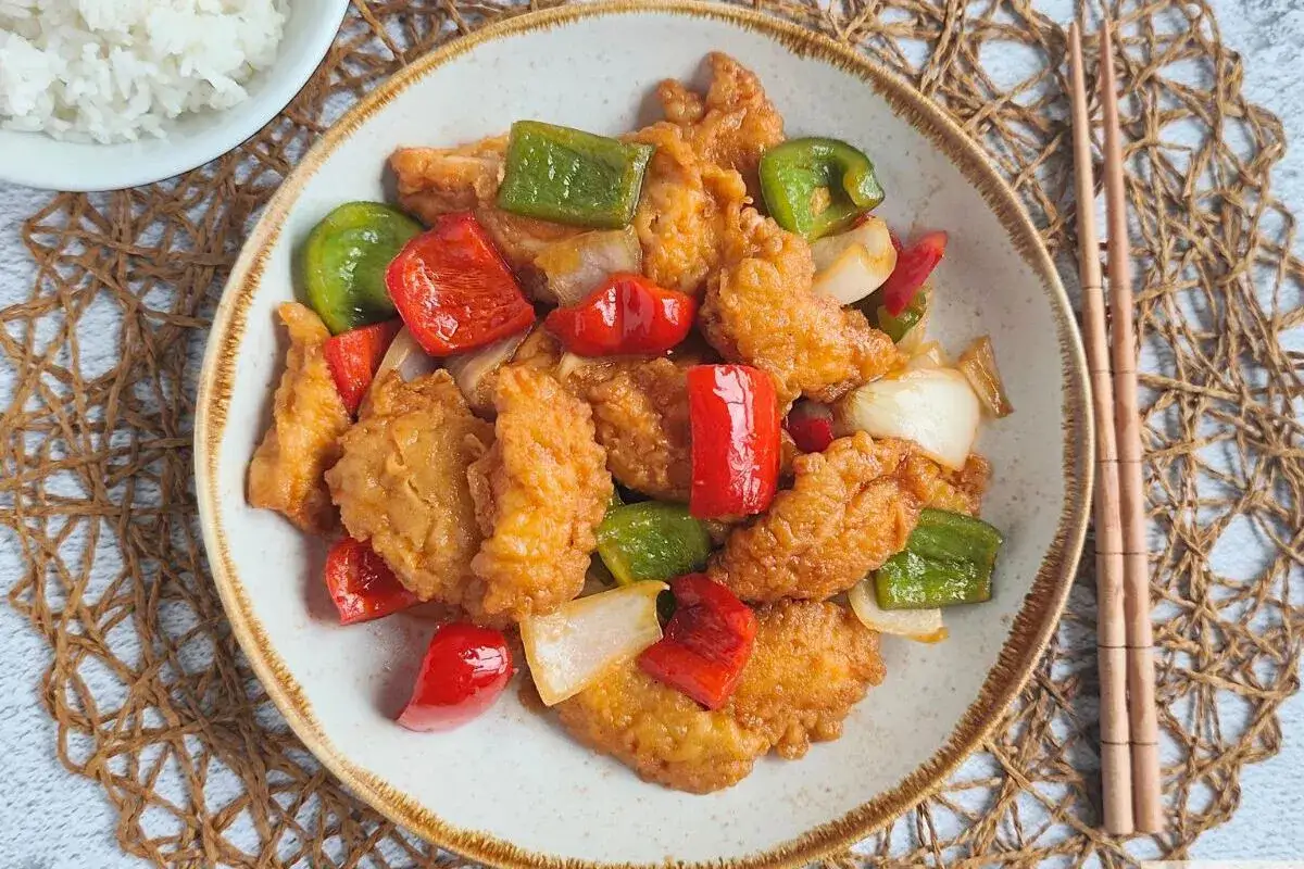 Delicioso pollo agridulce con pimientos rojos y verdes, y cebolla. Un plato vibrante y sabroso, listo para disfrutar.