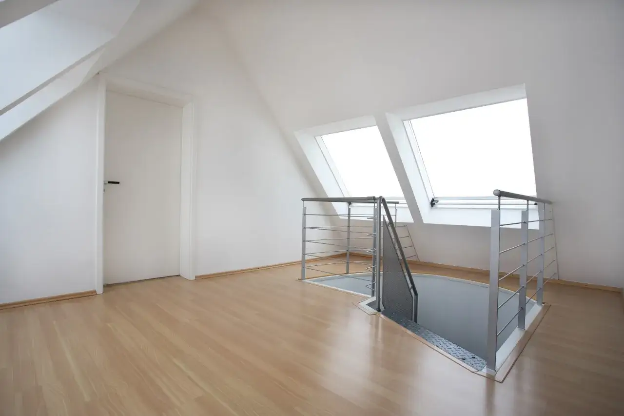 Nowe, jasne wnętrze z drzwiami i oknami dachowymi. Widoczne wejście na poddasze użytkowe z metalową balustradą.