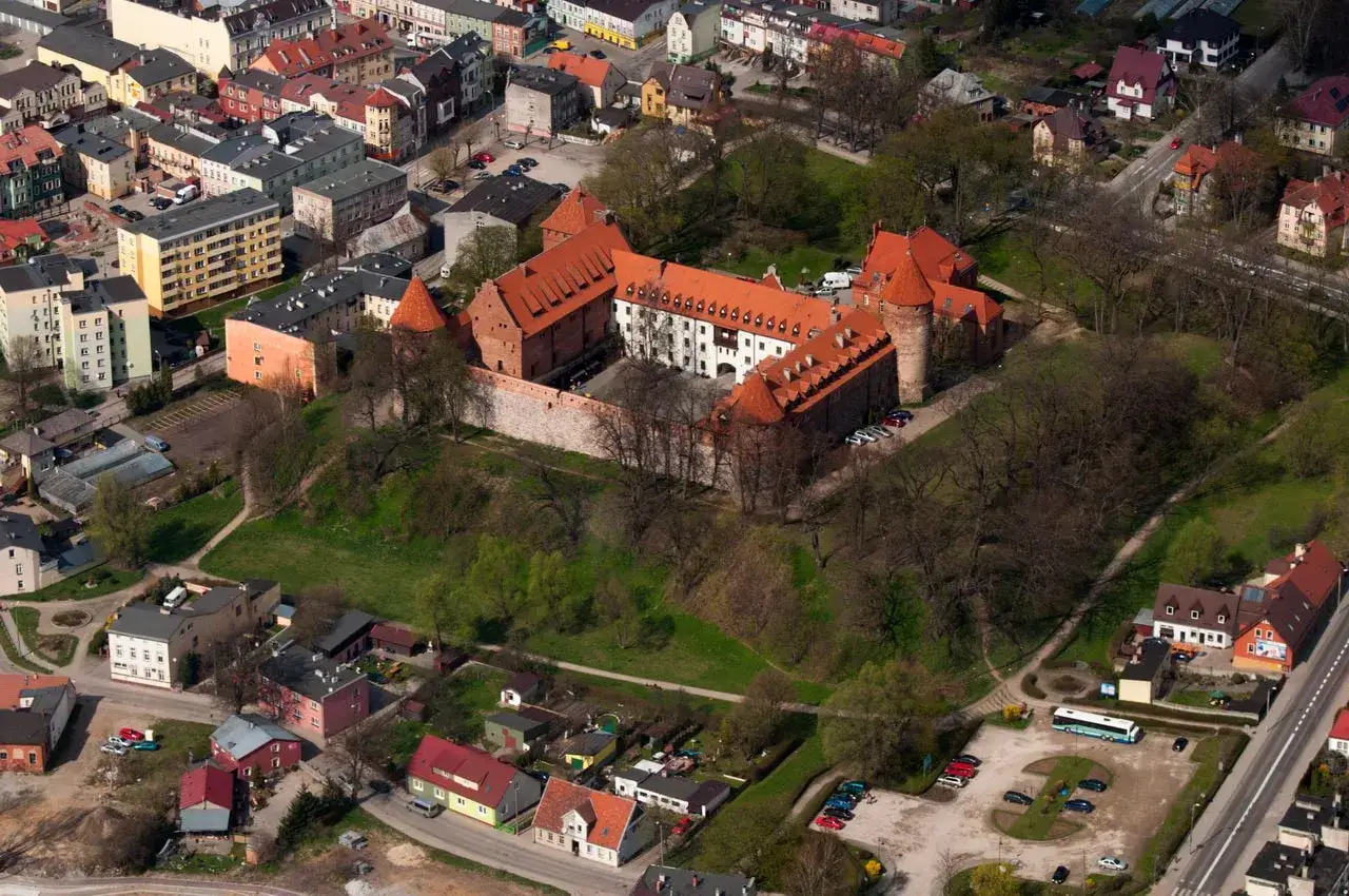 Zamek krzyżacki w Bytowie z lotu ptaka, otoczony zielenią i zabudowaniami miejskimi.