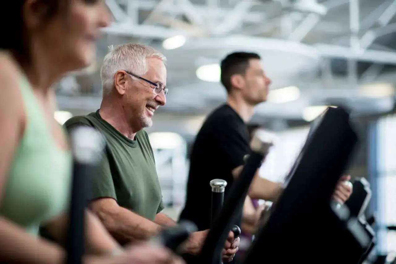 L&auml;chelnder Mann auf Laufband. Er genie&szlig;t das Training, auch wenn er sp&auml;ter sein Widerrufsrecht im Fitnessstudio pr&uuml;fen m&ouml;chte.