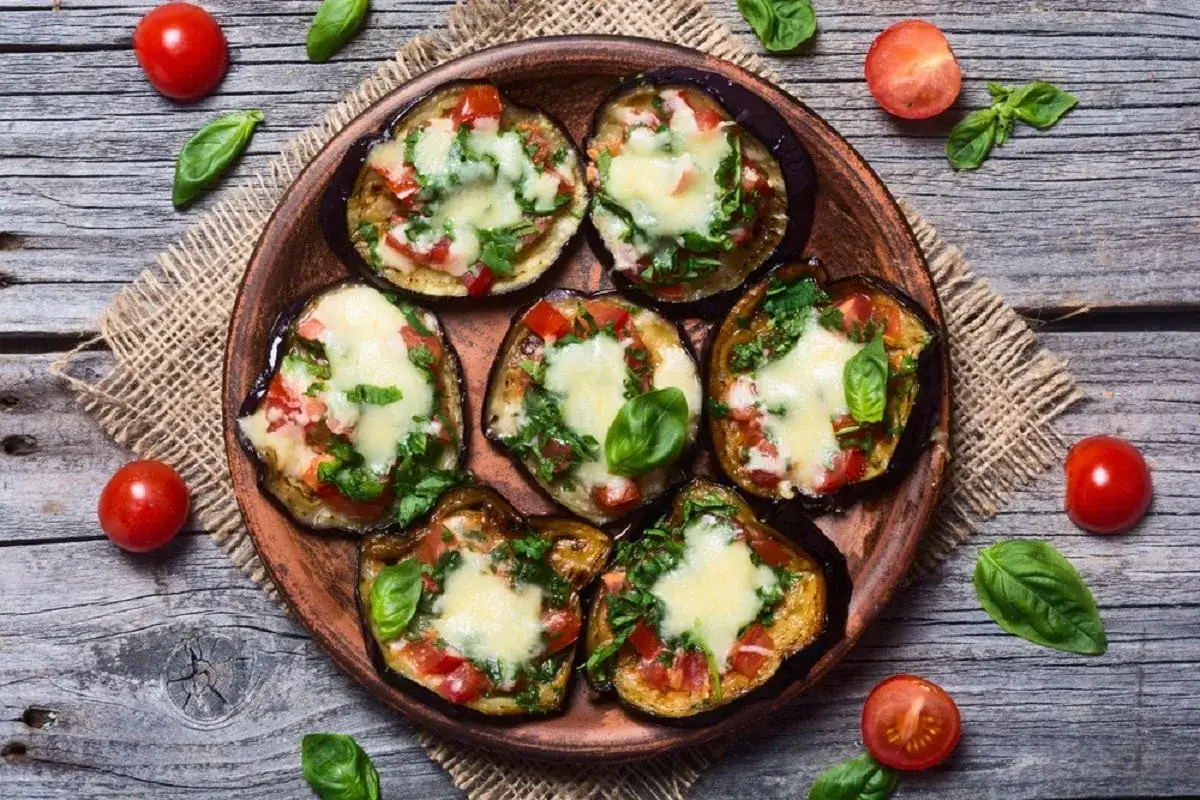 Fette di melanzane cotte al forno, condite con pomodoro, basilico e formaggio fuso, un piatto invitante di melanzane alla pizzaiola.