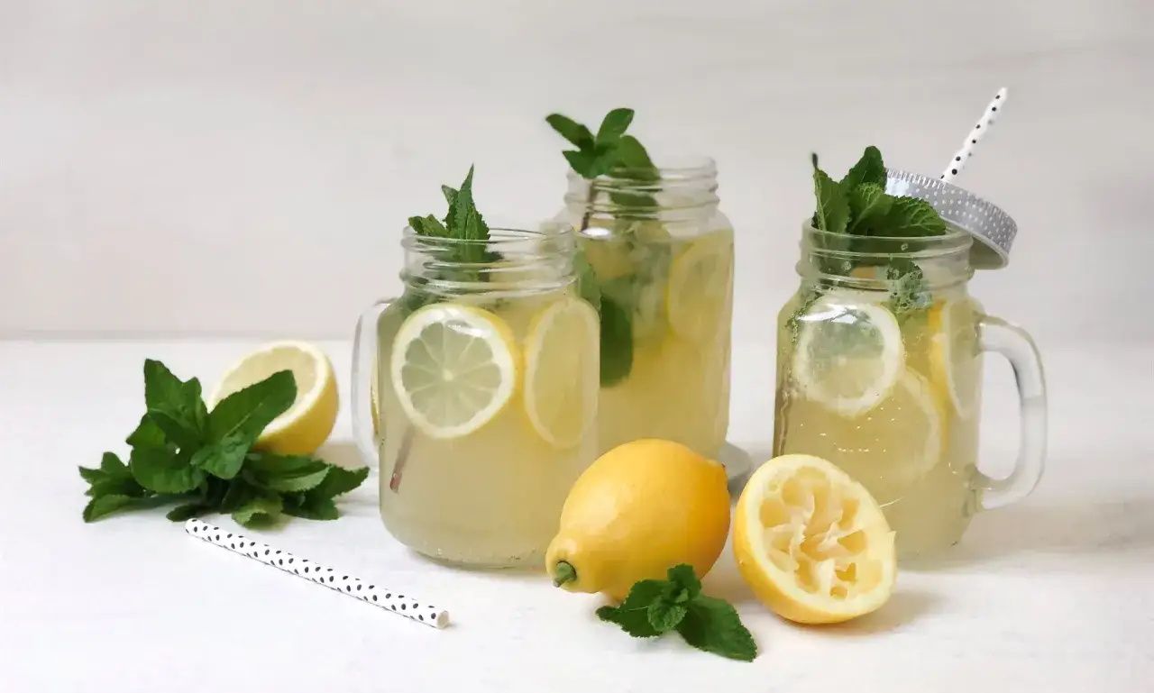 Erfrischende selbstgemachte Limonade in Einmachgläsern mit Zitronenscheiben und Minze. Perfekt für heiße Tage!