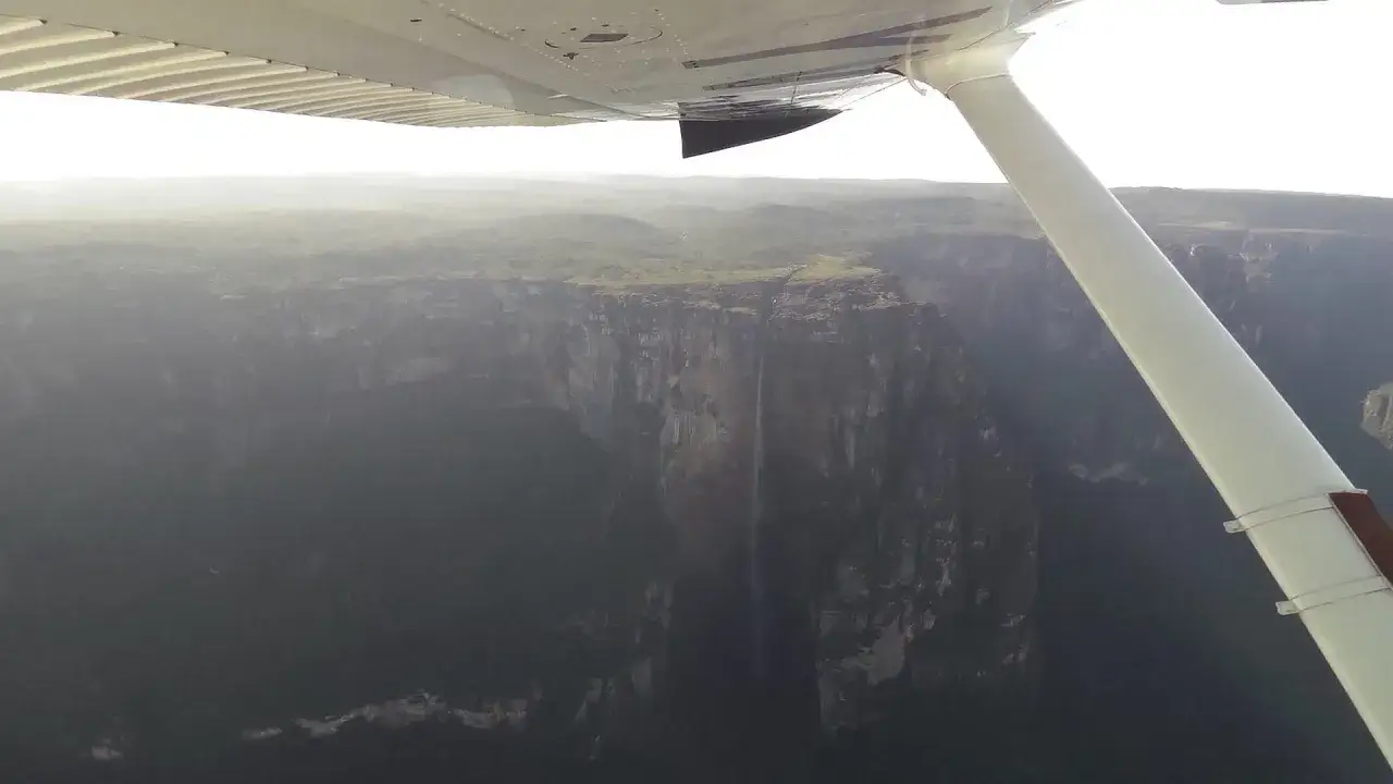 Widok z samolotu na najwyższy wodospad na świecie, Angel Falls, spadający z ogromnego klifu w dżungli.