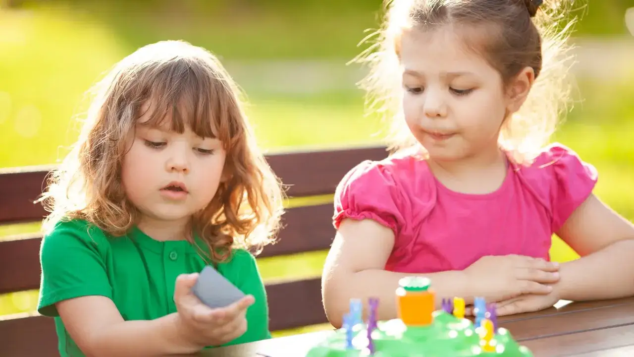 Zwei Kinder, vielleicht 3 Jahre alt, spielen drau&szlig;en mit einem Spiel.