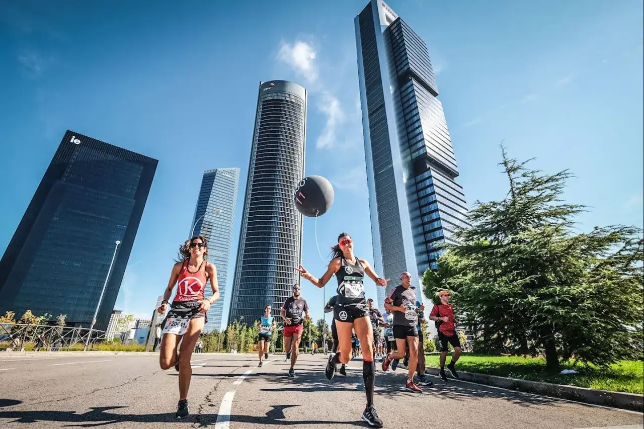 Des coureurs participent au semi marathon de Madrid, avec des gratte-ciel modernes en arri&egrave;re-plan.