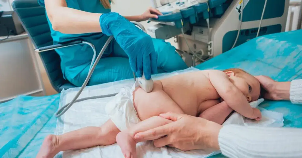 Lekarz wykonuje USG bioderek u noworodka, by upewnić się, że wszystko jest w porządku.