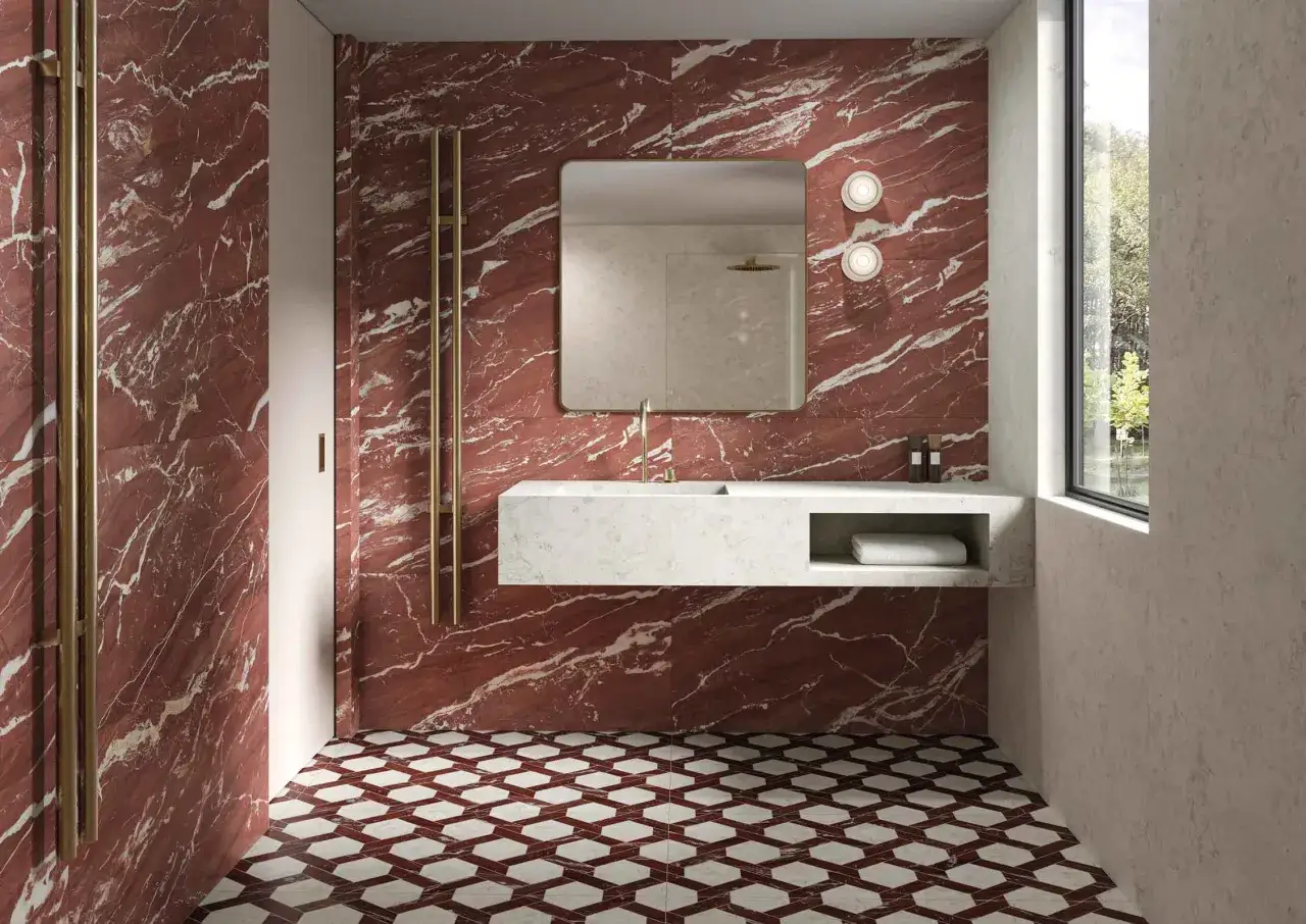 Ba&ntilde;o moderno con paredes de m&aacute;rmol rojo y blanco, suelo hexagonal y lavabo flotante. Varios tipos de revestimientos crean un espacio lujoso.