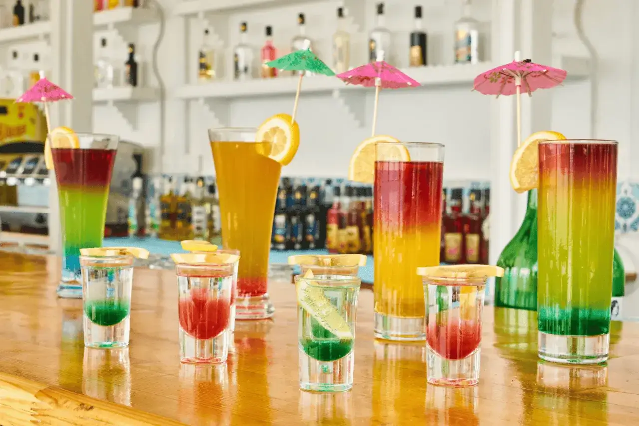 Kolorowe drinki przepisy na letnie popołudnie. Warstwowe shoty i wysokie kieliszki z owocami i parasolkami.