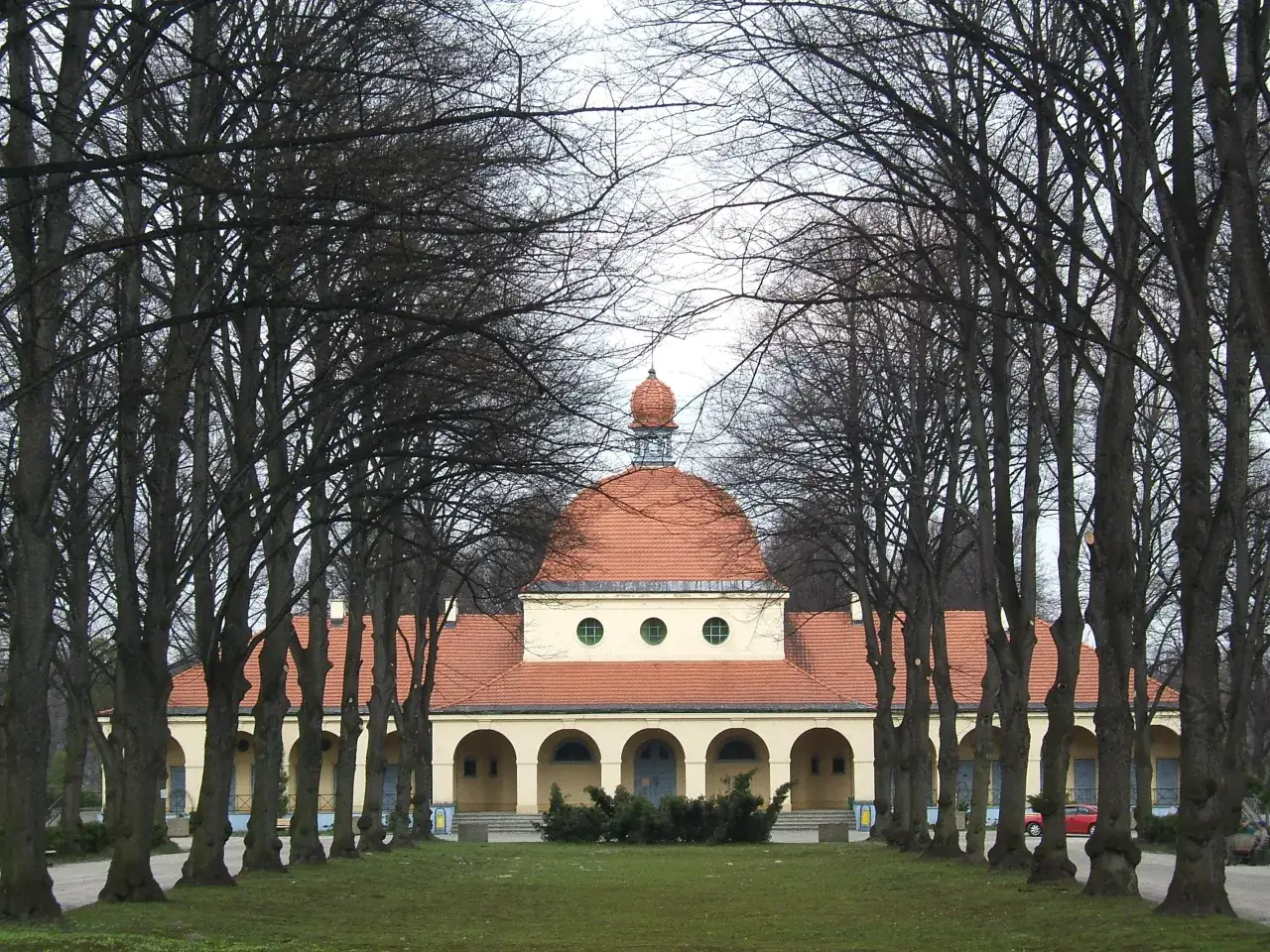 Aleja drzew prowadzi do budynku z kopułą na cmentarzu centralnym w Gliwicach.