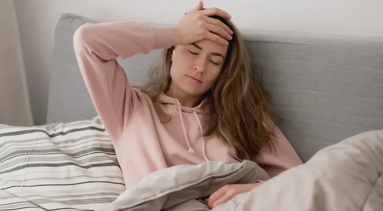 En kvinna med handen p&aring; pannan i s&auml;ngen, k&auml;nner &aring;ngest p&aring; morgonen och depression.