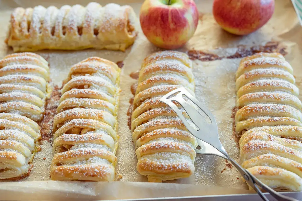 Frisch gebackene Apfeltaschen, best&auml;ubt mit Puderzucker, warten auf das Servieren. Ein k&ouml;stliches Apfeltaschen Rezept zum Nachbacken.