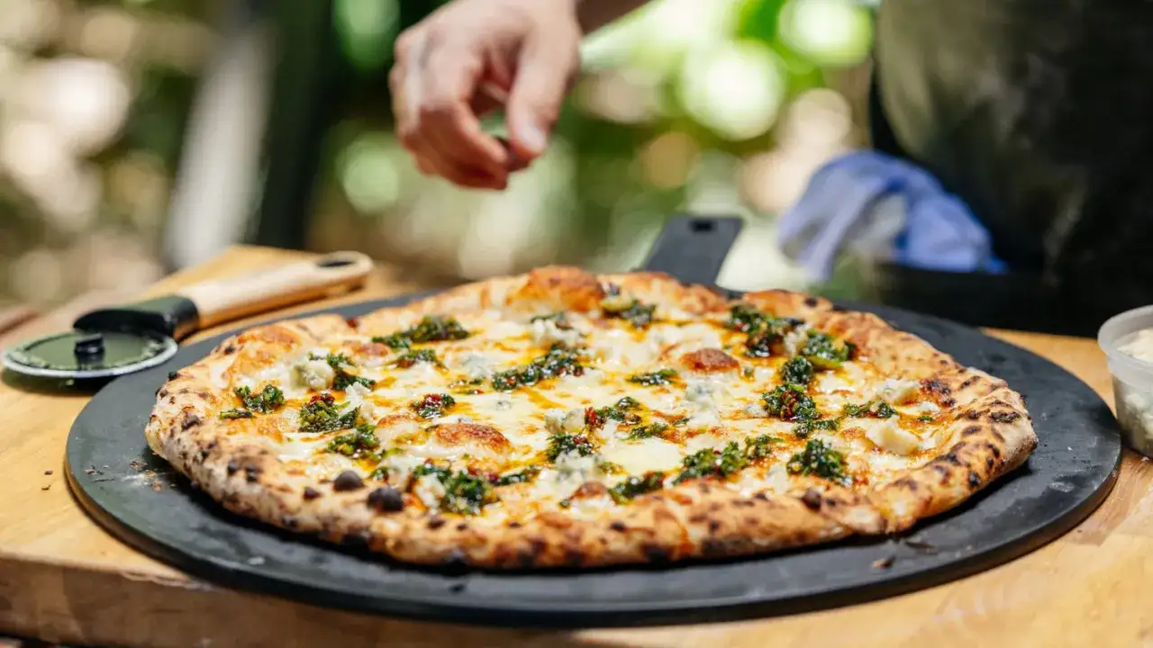 Eine köstliche Quattro Formaggi Pizza mit geschmolzenem Käse und grünen Kräutern, bereit zum Anschneiden.